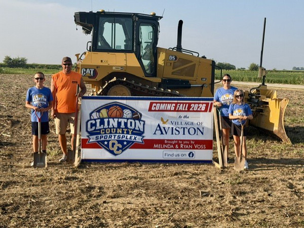 Ryan and Melinda Voss standing with the children and a banner by a tractor