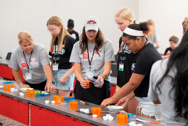 Dr Jessica Kerr works with students in Rxplorers camp at a table mixing sample medicines