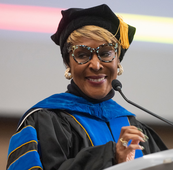 Dr P speaking at podium in commencement attire