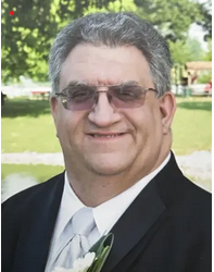 Portrait of Ed Knowles in a suit and white tie outside on a sunny day