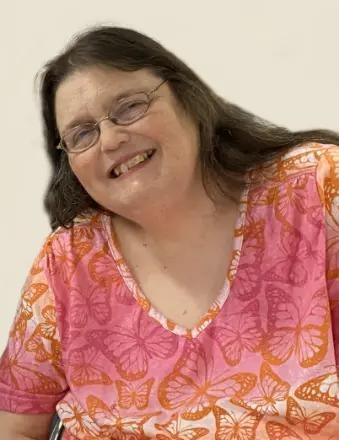 Portrait of Hardwick, smiling and wearing a brightly colored blouse with butterflies on it.