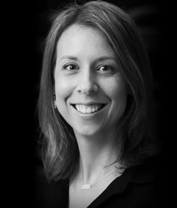 Black and white portrait of Lindsay Schmidt, smiling and wearing a necklace and earrings.