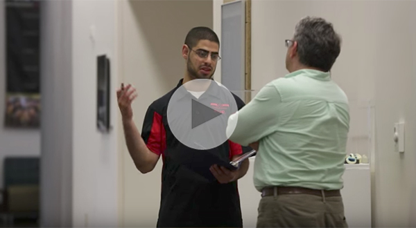 male student talking to professor in hallway