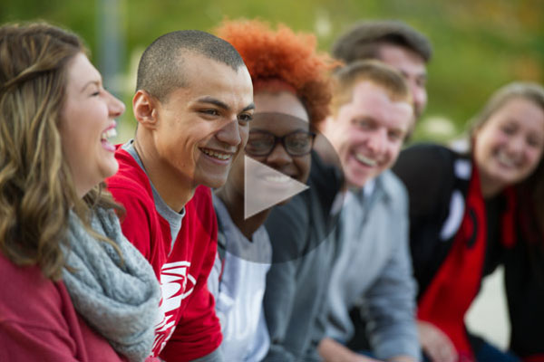 A group of students laughing with video play button