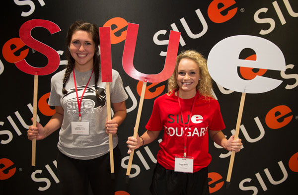 Two female students holding letters S-I-U-E in front of photo backdrop