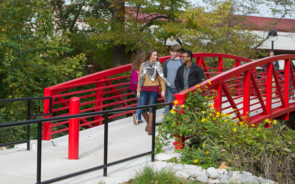 Students walking across a red bridge