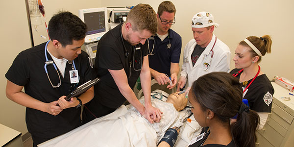 nursing students in scrubs working in simulation lab
