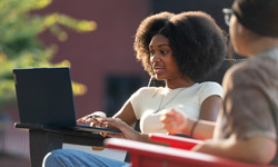 SIUE students working on a laptop outside of the MUC.