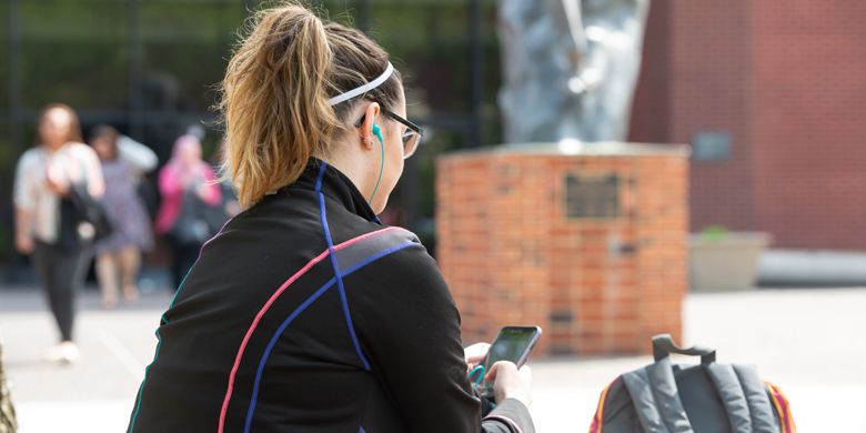 Student looking on her phone at SIUE on the Stratton Quadrangle.